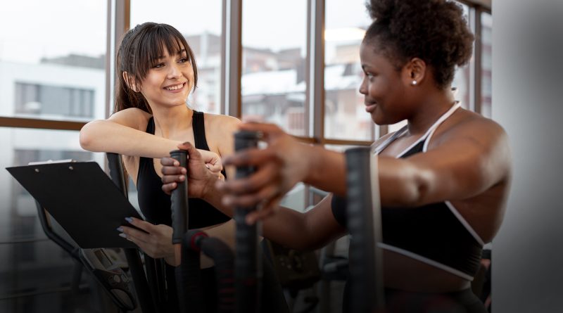 Mulher conversando com personal trainer para iniciar treino na academia