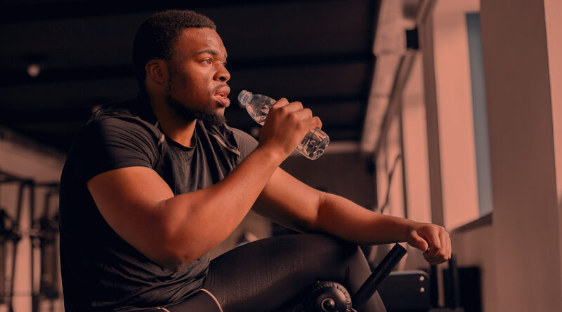 Homem negro bebendo água durante treino.