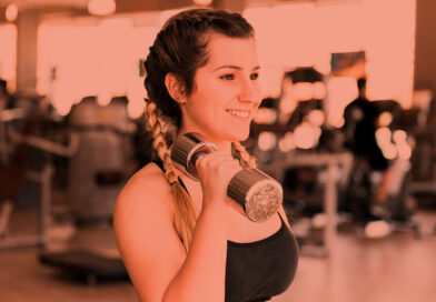 Mulher treinando com halteres na academia.