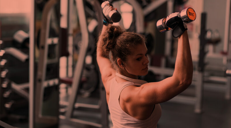 Mulher treinando braços na academia de musculação.