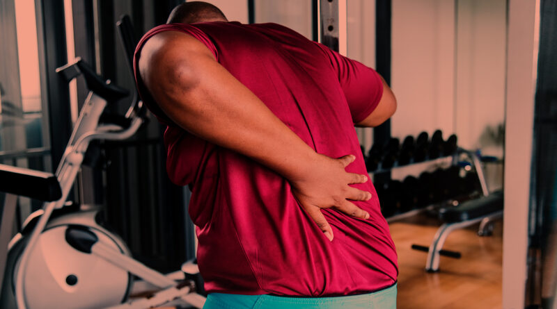 Homem com dores nas costas após treino de musculação