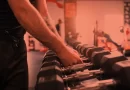 Homem pegando halteres em treino avulso. Foto: Freepik